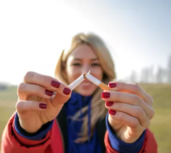 Jeune femme blonde souriant et cassant une cigarette