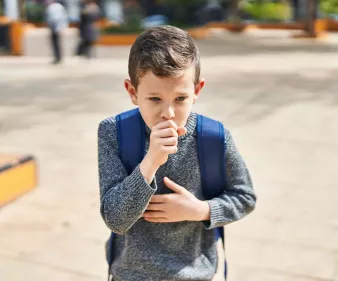 Enfant avec un cartable qui tousse