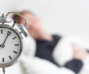 Jeune fille dormant, avec un réveil en premier plan.
