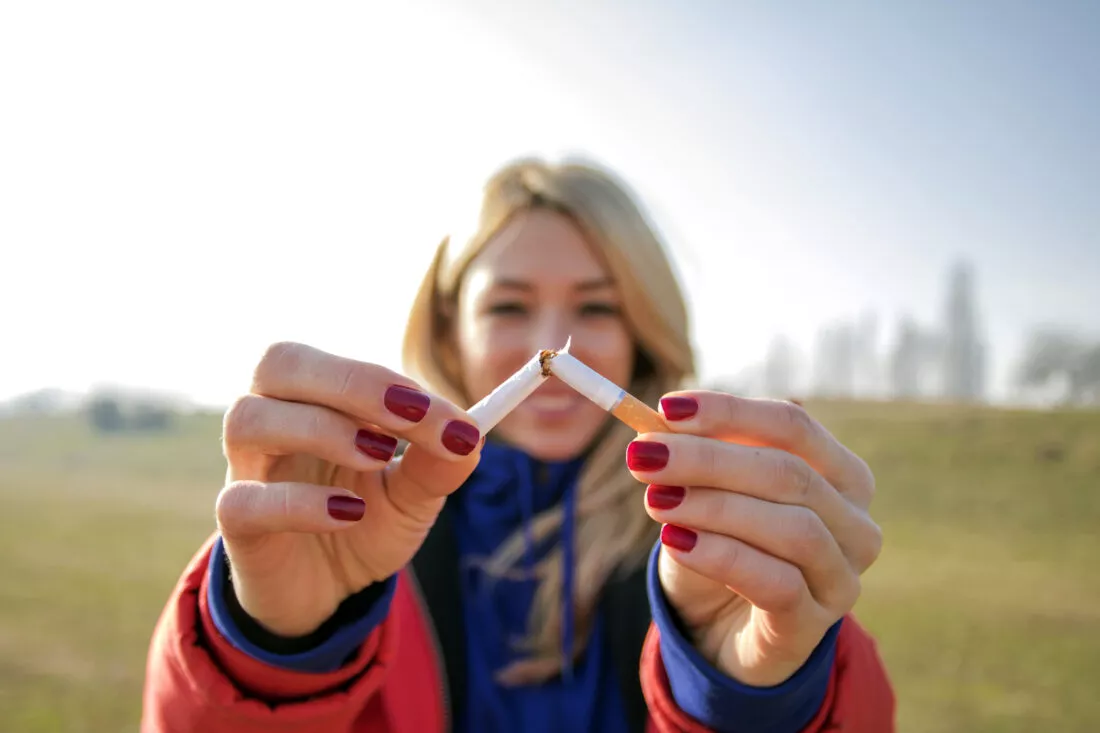 Jeune femme blonde souriant et cassant une cigarette
